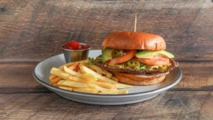 Delicious Hamburguesa Mexicana topped with avocado, jalapeños, melted cheese, and fresh vegetables, served on a toasted bun with a side of crispy fries.