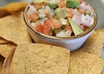 Ceviche: "A colorful dish of fresh ceviche featuring marinated shrimp, diced tomatoes, onions, cilantro, and avocado, served with crisp tortilla chips on the side."